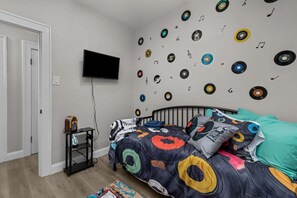 Ein Schlafzimmer mit einem Bett, einem an der Wand montierten Fernseher und einer Wand, die mit Schallplatten dekoriert ist.