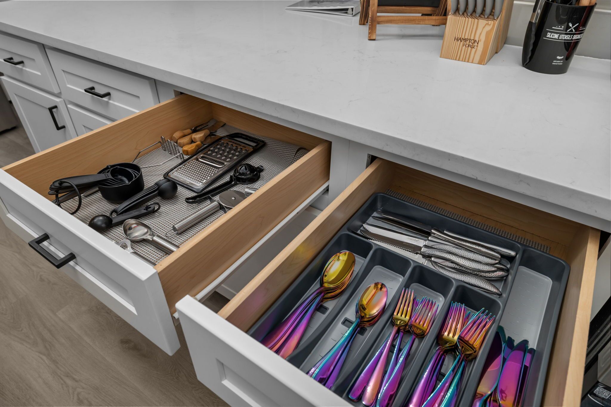 A kitchen drawer with utensils and a cutting board.