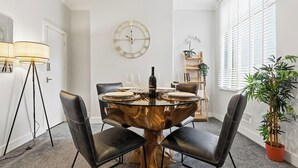 A dining area with a round table, black chairs, a wall clock, and a potted plant. - Stunning 3B Home, ideal for leisure & contractors (Clitheroe)