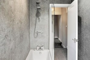 Un baño moderno con bañera, ducha e inodoro.