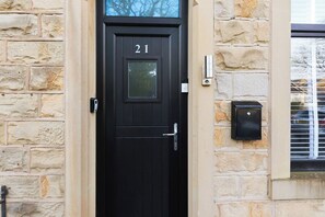 A black door with the number 21, a mailbox, and a window with blinds.