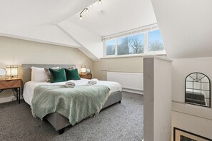 Un dormitorio con cama, mesita de noche, ventana y radiador.