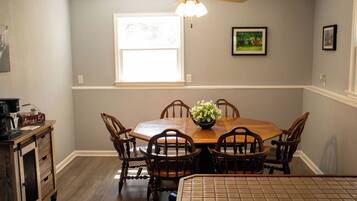 A dining area with a wooden table, chairs, a ceiling fan, and a window with natural light.