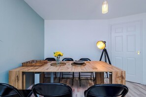 A dining area with a wooden table, chairs, a vase with yellow flowers, and a floor lamp. - Spacious 6 bedroom house, with private parking (Manchester, London)