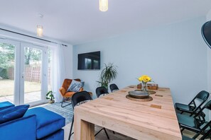 Un comedor moderno con una mesa de madera, sillas y un televisor montado en la pared.