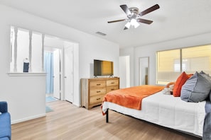 A bedroom with a bed, a dresser, a ceiling fan, a window with blinds, and a door leading to another room. - Peaceful Lubbock Retreat with Private Indoor Atrium (Lubbock)