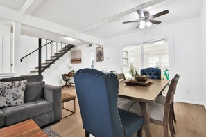 Un salon moderne avec un canapé, une table à manger et des chaises, un escalier et un ventilateur de plafond.