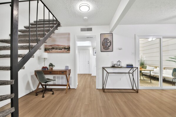 A modern interior with a staircase, a desk, a chair, and a sofa. - Peaceful Lubbock Retreat with Private Indoor Atrium (Lubbock)