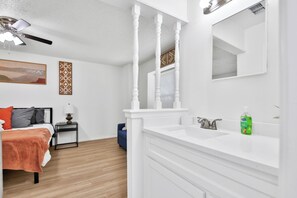 Une salle de bain moderne avec un meuble-lavabo blanc, un grand miroir et un ventilateur de plafond.