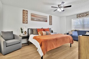 Une chambre à coucher moderne avec un lit, un bureau, une chaise et un canapé.
