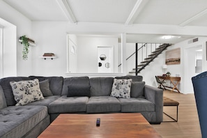 A modern living room with a grey sectional sofa, a wooden coffee table, and a staircase leading to another level. - Peaceful Lubbock Retreat with Private Indoor Atrium (Lubbock)