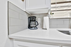 A kitchen with white tiles, a coffee maker, and a paper towel dispenser. - Peaceful Lubbock Retreat with Private Indoor Atrium (Lubbock)
