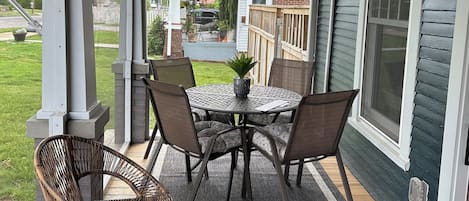 A covered porch with a table and chairs, a fan, and a view of the backyard.
