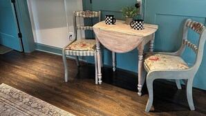 A room with teal walls, a flat-screen TV mounted on the wall, a small round table with two chairs, and a patterned rug on the floor. - The Fox Den in delightful Columbia (Columbia)