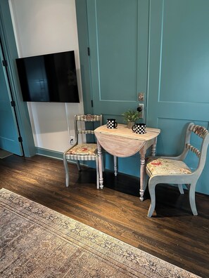 A room with teal walls, a flat-screen TV mounted on the wall, a small round table with two chairs, and a patterned rug on the floor. - The Fox Den in delightful Columbia (Columbia)