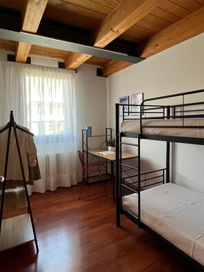 Une chambre avec des lits superposés, un bureau, une chaise et un porte-manteau.