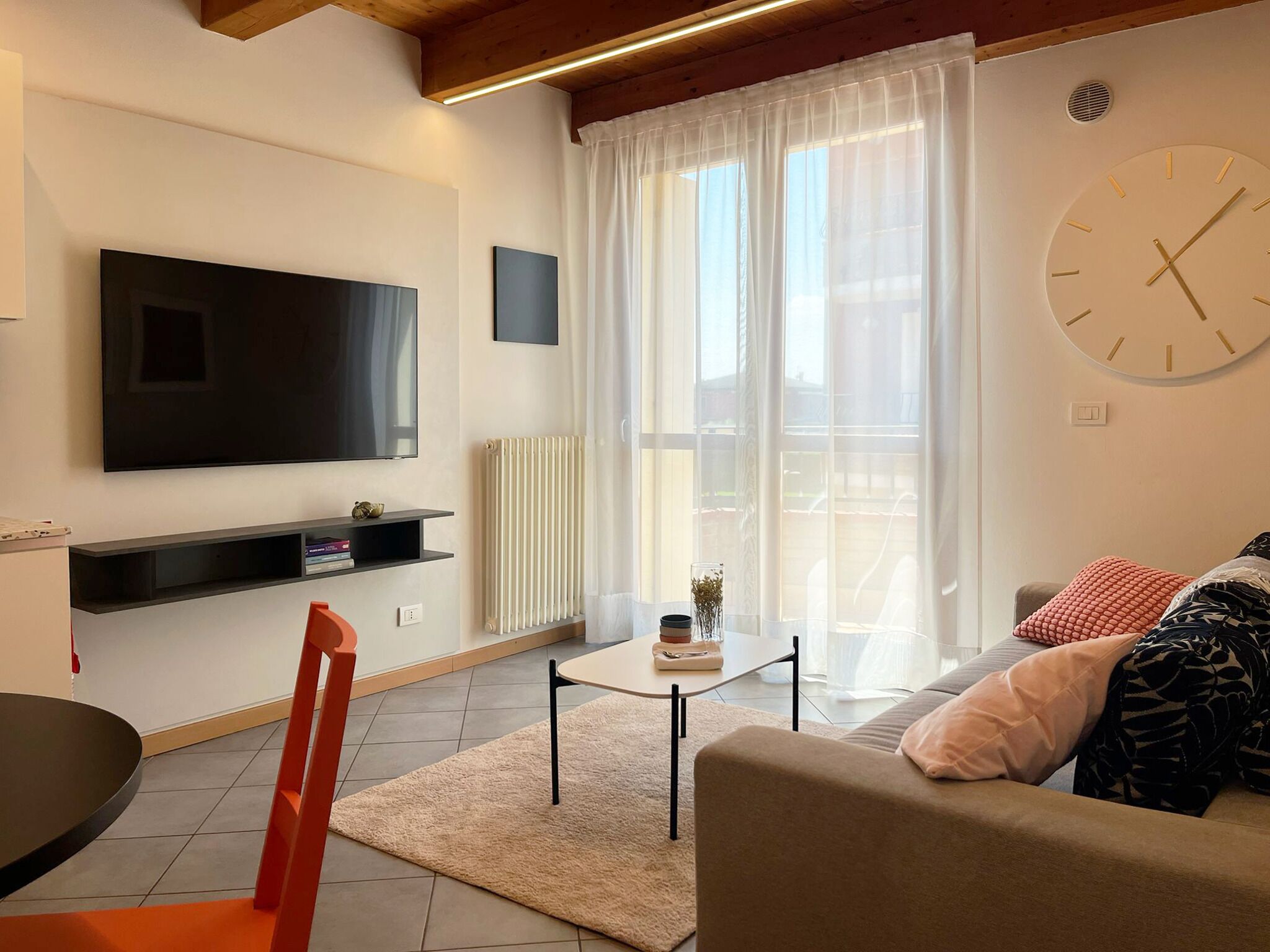 A modern living room with a flat-screen TV, a sofa, a coffee table, and a dining area.