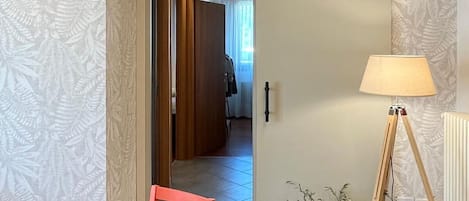 Una habitación con techo de madera, puerta corredera, una mesa con fruta, una lámpara y una planta en maceta.