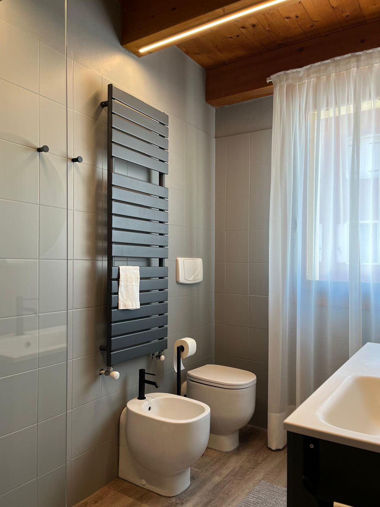 A modern bathroom with a toilet, bidet, and a towel rack.