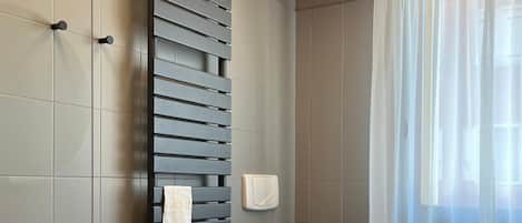 A modern bathroom with a toilet, bidet, and a towel rack.