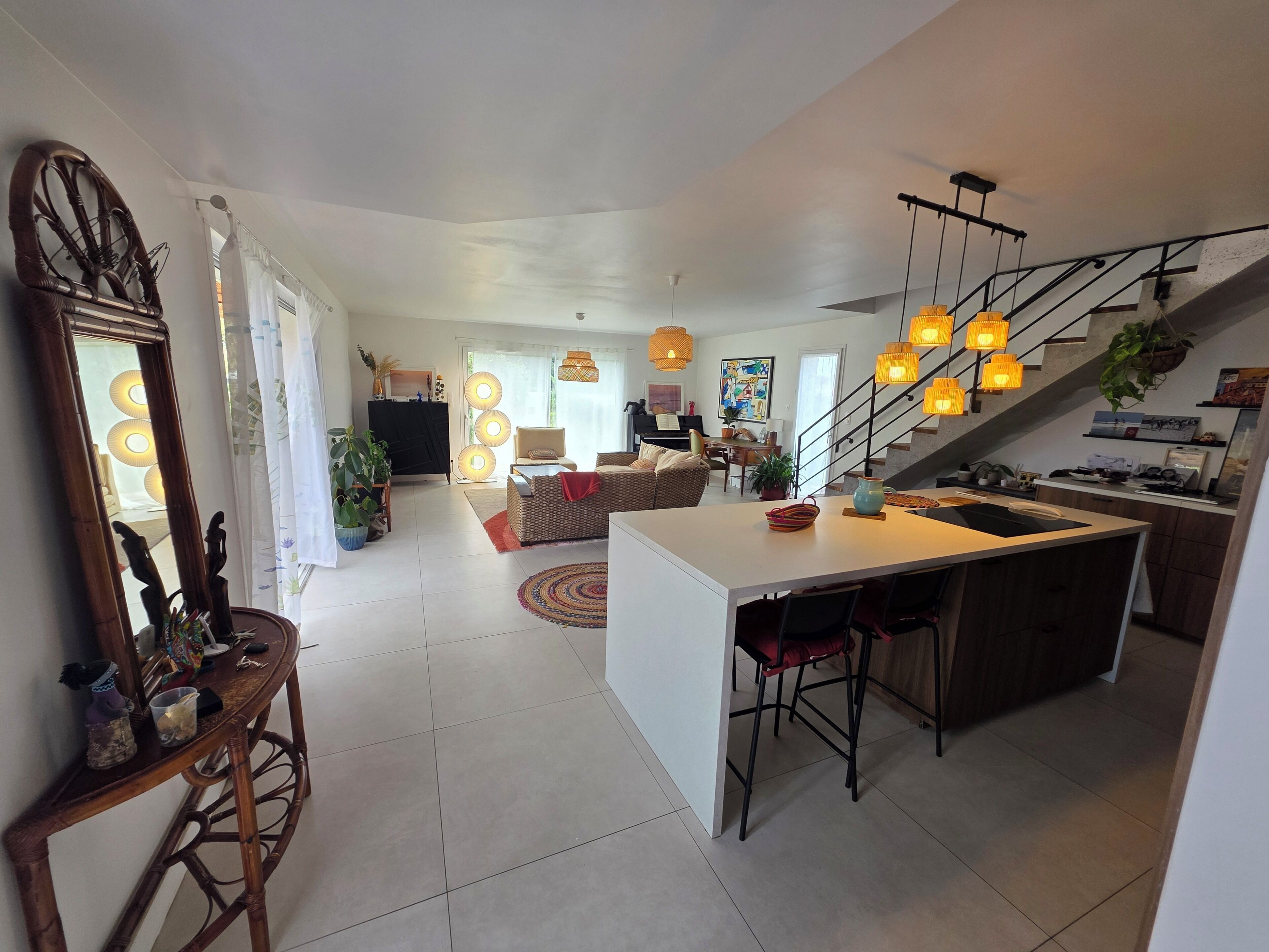Un vaste espace de vie comprenant un îlot central, un coin repas et un escalier menant à l’étage supérieur.