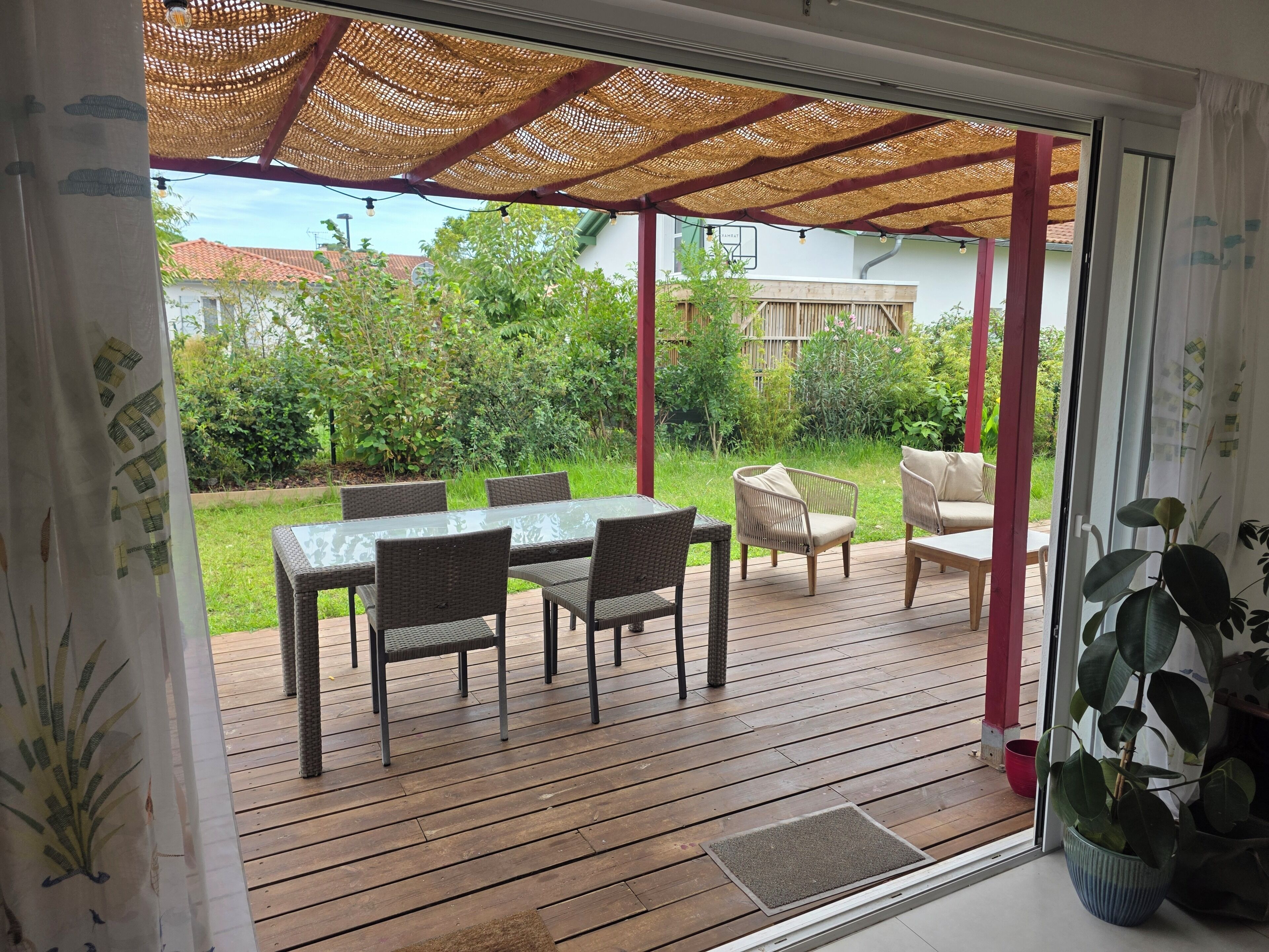 An outdoor patio with a table and chairs, a covered seating area, and a view of the surrounding greenery.