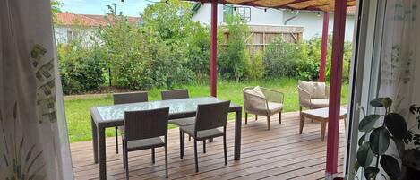 An outdoor patio with a table and chairs, a covered seating area, and a view of the surrounding greenery.
