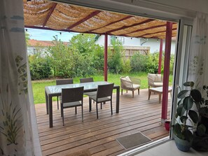 An outdoor patio with a table and chairs, a covered seating area, and a view of the surrounding greenery. - A 4-bedroom family home located between Bayonne, Biarritz, and the Landes region. (TARNOS)