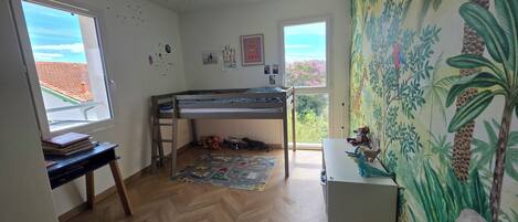 Habitación infantil con literas, un escritorio y una ventana con vistas.