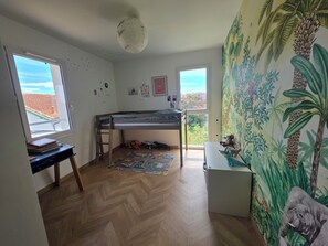 Ett barnrum med en våningssäng, ett skrivbord och ett fönster med utsikt.