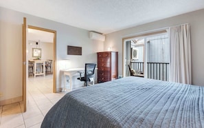 Ein Hotelzimmer mit Bett, Schreibtisch, Stuhl, Kleiderschrank und einem Balkon mit Vorhängen.