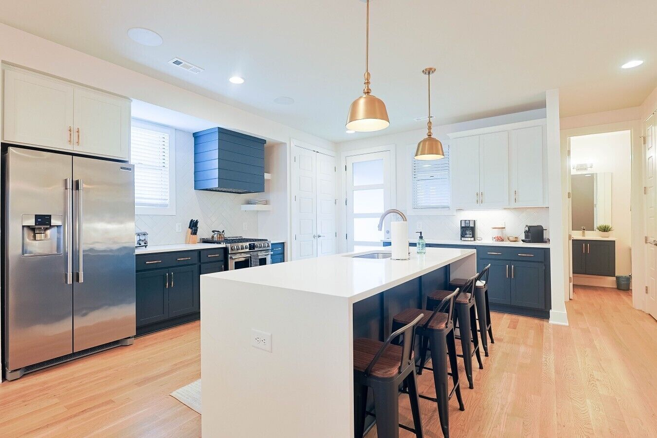 A modern kitchen with a central island, stainless steel appliances, and bar stools.