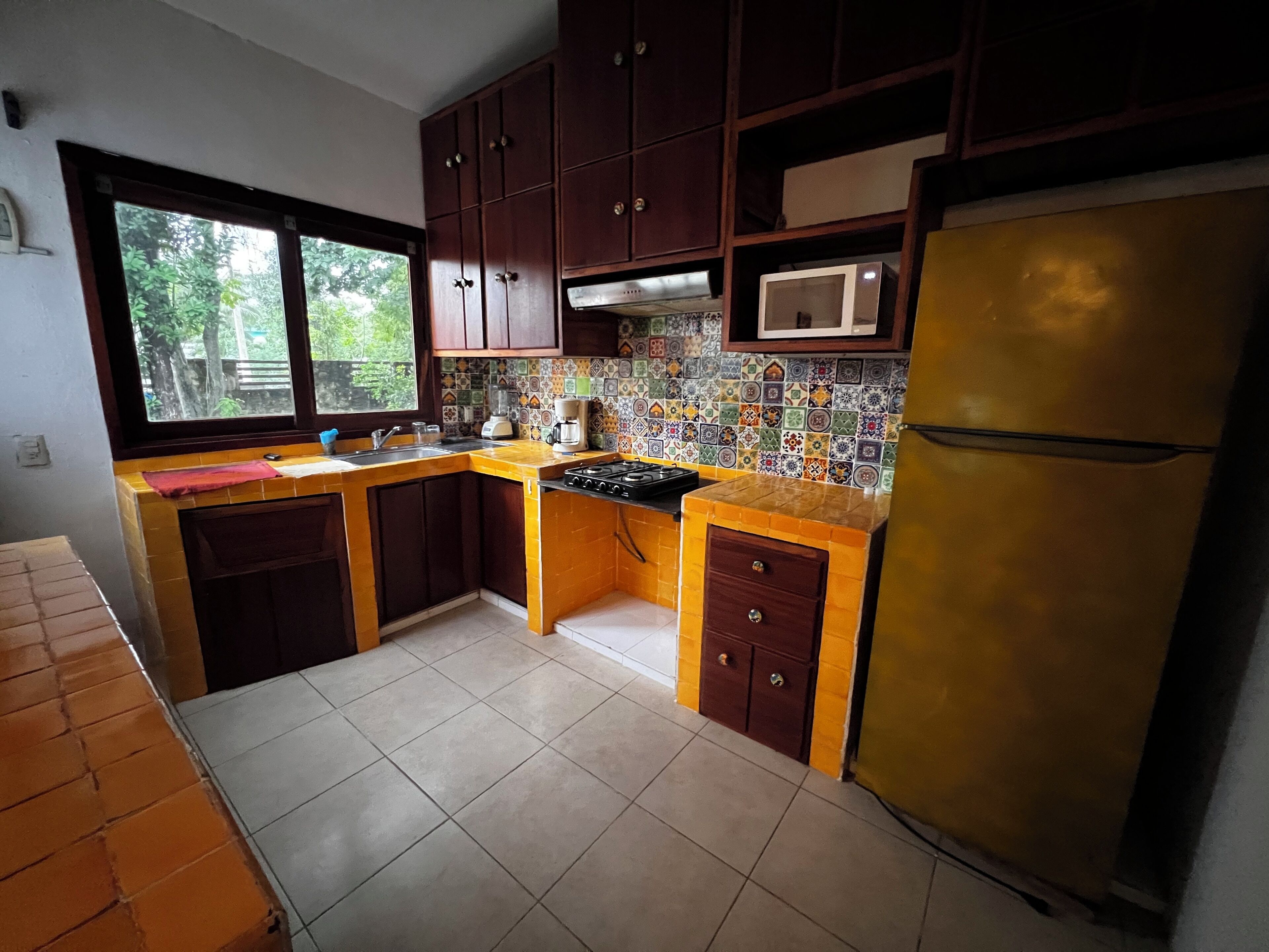 A kitchen with a tiled backsplash, a stove, a sink, and a refrigerator.