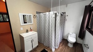 A bathroom with a white sink, mirror, toilet, and shower curtain. - House with a spacious yard surrounded by jungle and trees, ideal for families (Xpujil)