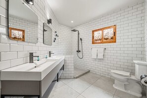 A modern bathroom with white subway tiles, a large mirror, a double sink vanity, a shower, and a toilet. - 6BR Aruba Villa w/ Pool | Near Palm & Eagle Beach (Noord)