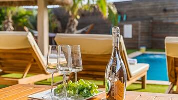 A table with a bottle of white wine, three glasses, and a plate of grapes.