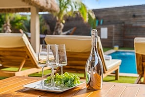A table with a bottle of white wine, three glasses, and a plate of grapes. - 6BR Aruba Villa w/ Pool | Near Palm & Eagle Beach (Noord)