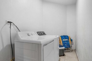 Un espace buanderie équipé d’un lave-linge et d’un étendoir.