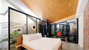 Quarto moderno com cama de madeira, parede de vidro e vista para o exterior.
