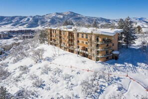 Un hôtel à plusieurs étages, doté de balcons, entouré d’arbres et de montagnes couverts de neige.