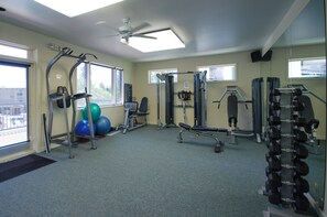 Une salle de sport équipée de matériel d’exercice, dotée d’un ventilateur de plafond et de grandes fenêtres.