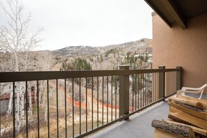 Un balcon donnant sur un paysage montagneux, un banc en bois et une rambarde.