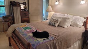 Une chambre à coucher avec un lit, une couette, une lampe, une commode et un miroir.