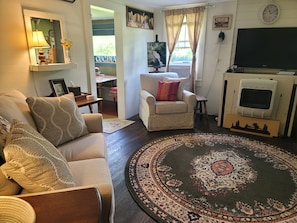 A living room with a sofa, armchair, and a patterned rug. - Peaceful and cozy 1-bedroom historic creek-side cabin in Glenville with AC (Glenville)