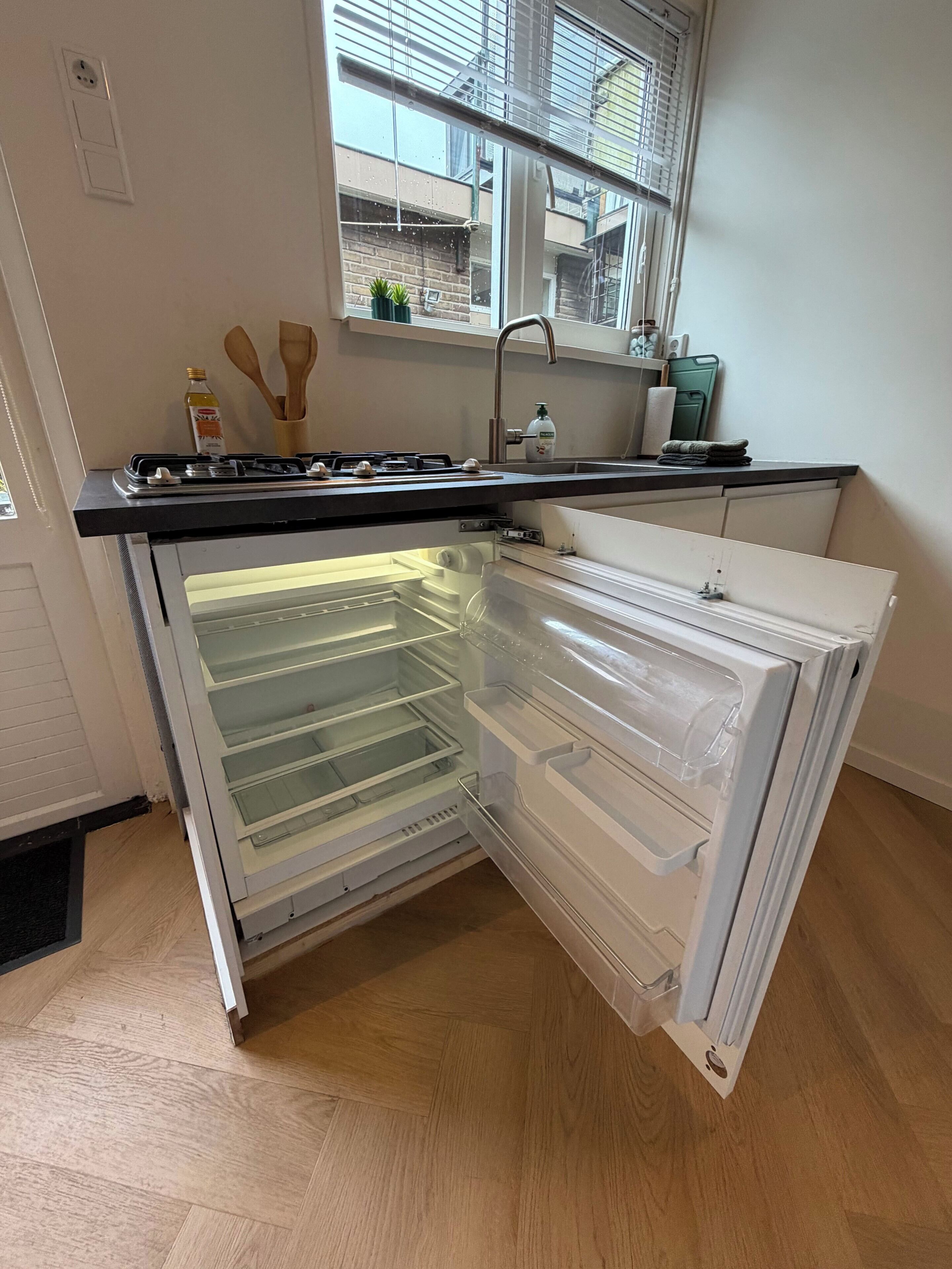 Eine Küche mit Einbaukühlschrank, einem Fenster und einer Spüle.