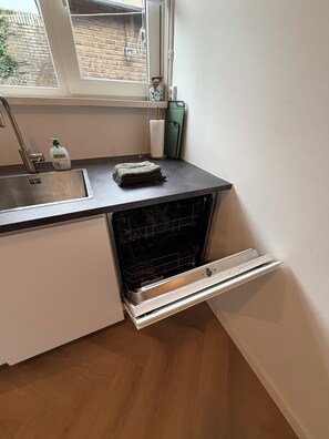Una cuina amb forn integrat, un rentapeus i una finestra.