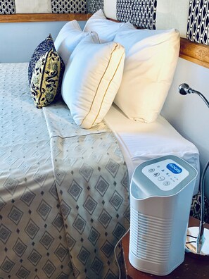 A bed with a patterned bedspread, a pillow with a decorative cover, and a bedside table with a device. - A/C True Blue Apt base -perfect for SGU Airport - Yacht life, Beach, Fast WiFi (Saint George's)