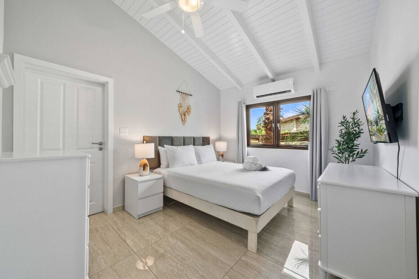 Une chambre d’hôtel moderne équipée d’un lit, de tables de chevet, d’un téléviseur et d’un appareil de climatisation.