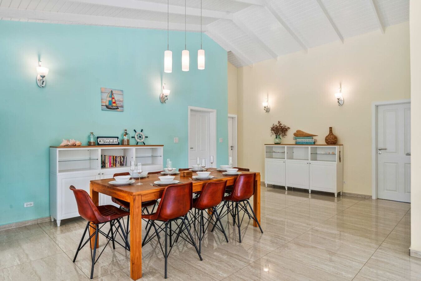 Un coin repas avec une table en bois dressée pour six personnes, entourée de chaises.
