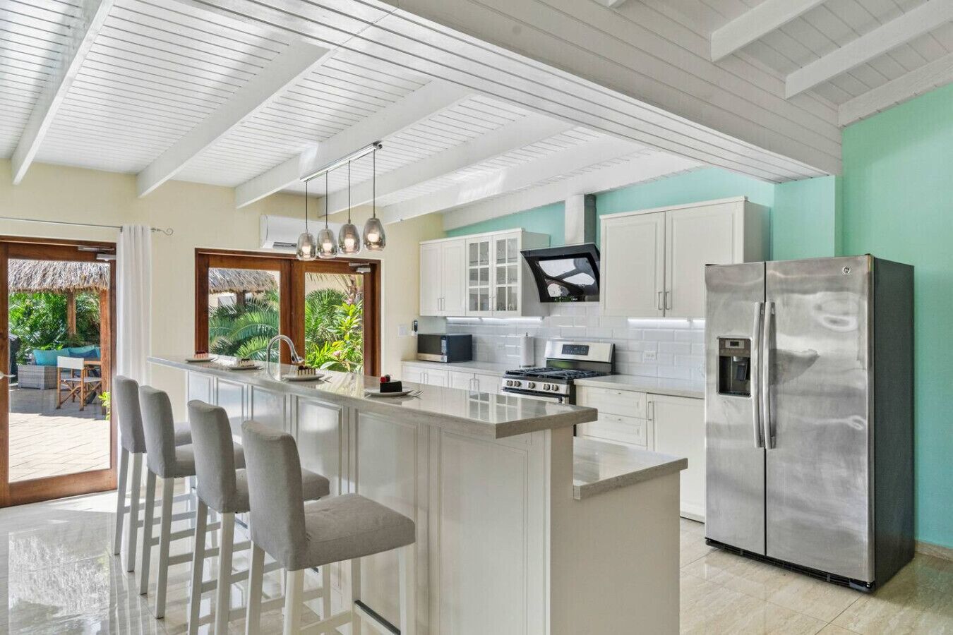 Een moderne keuken met een centraal eiland, barstoelen, een roestvrijstalen koelkast en uitzicht op het buitengebied.